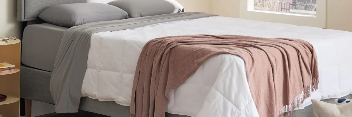 Purple branded soft stretch sheets on a modern bed in a neutral-toned bedroom.